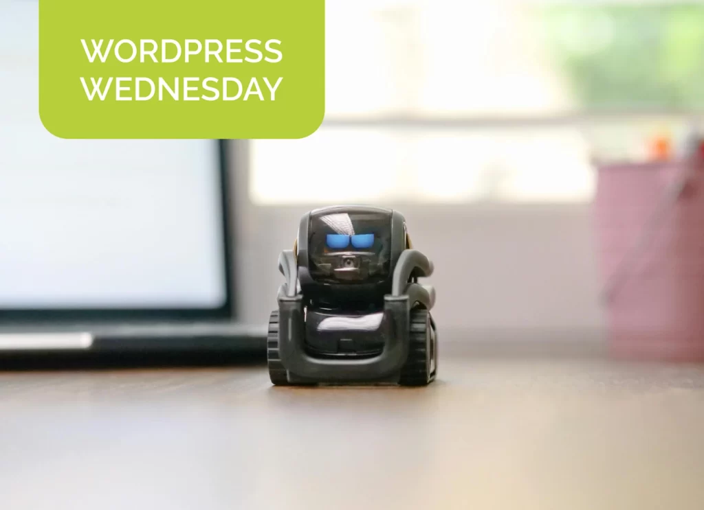 a small robot sits on top of a table next to a computer