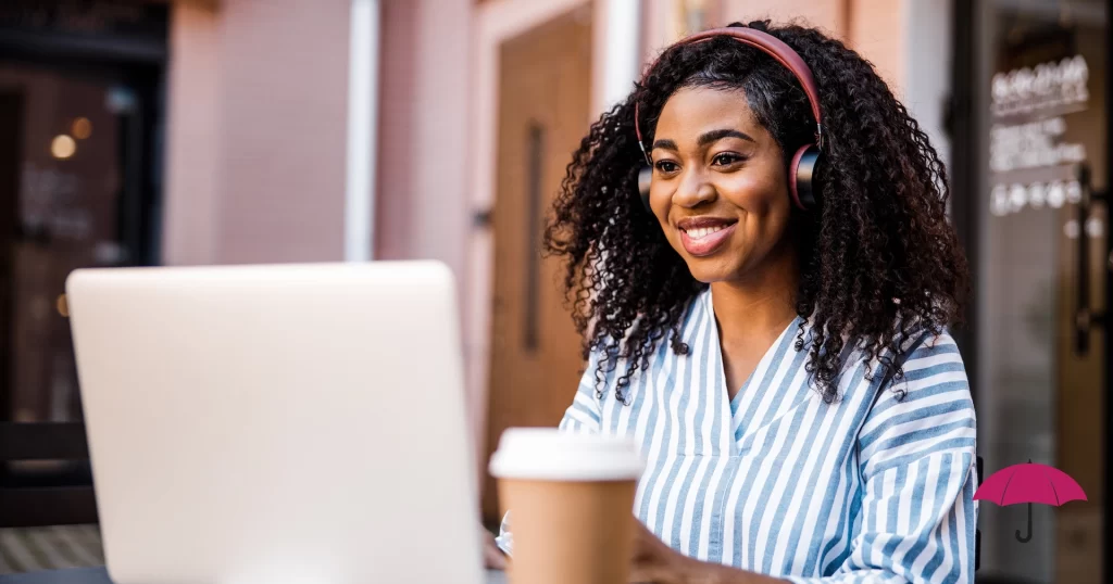 a woman wearing headphones and drinking coffee is smiling because she is happy with a website’s user experience